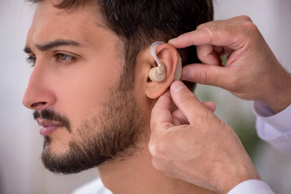 Jovem paciente do sexo masculino com problemas auditivos visitando médico velho otor — Fotografia de Stock