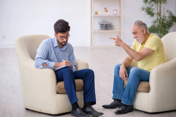 Oude man op bezoek bij jonge mannelijke psychotherapeut — Stockfoto