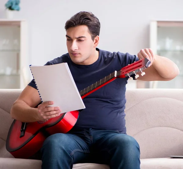 Mladý muž cvičí doma na kytaru — Stock fotografie