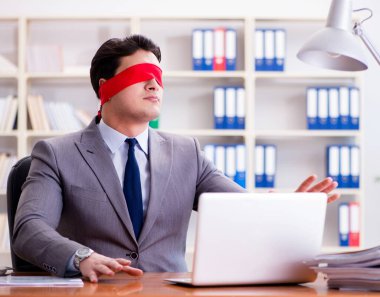 Ofiste masasında oturan gözü bağlı iş adamı.