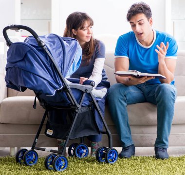 Bebekleri bebek arabasında oturan genç ebeveynler.