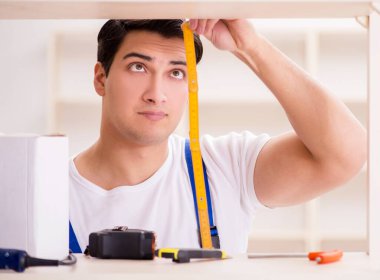 İşçi adam montaj kitaplığını tamir ediyor