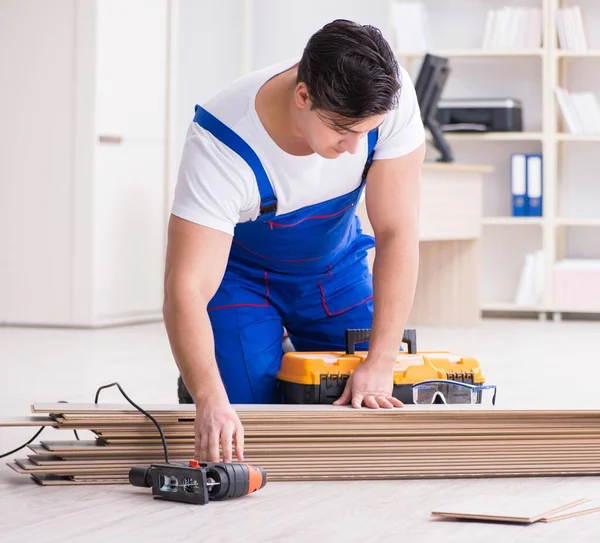 Giovane lavoratore che lavora su pavimenti in laminato — Foto Stock