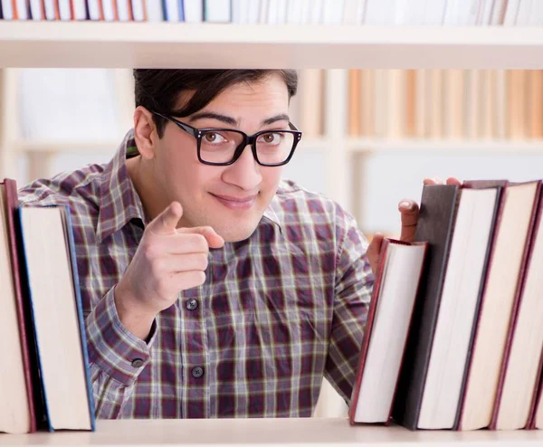 Jeune étudiant à la recherche de livres dans la bibliothèque du collège — Photo