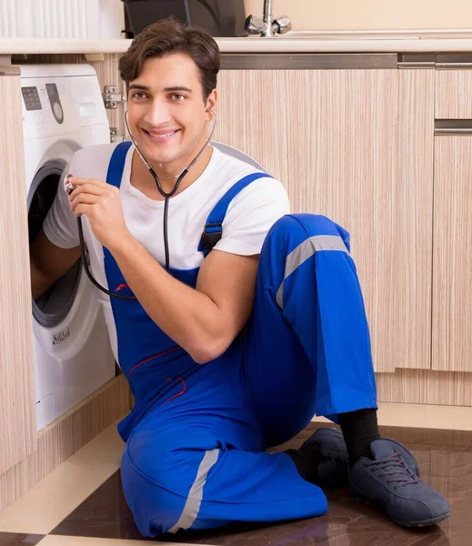 Tamirci mutfakta çamaşır makinesini tamir ediyor. — Stok fotoğraf