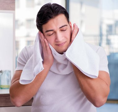 Genç yakışıklı adam yüz kremi sürüyor.