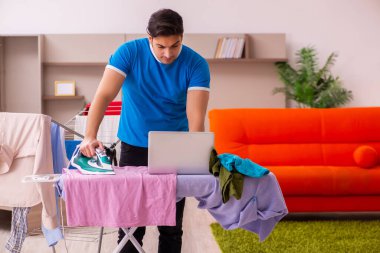 Genç adam evde ütü yapıyor.