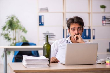 Genç alkol bağımlısı çalışan ofiste oturuyor.