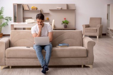 Genç erkek öğrenci salgın sırasında evde çalışıyor.