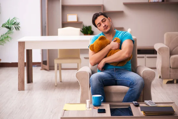 Young man sitting with bear toy at home — Stock Photo, Image