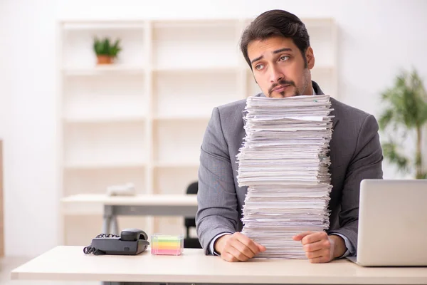 Jonge mannelijke werknemer ongelukkig met overmatig werk in het kantoor — Stockfoto