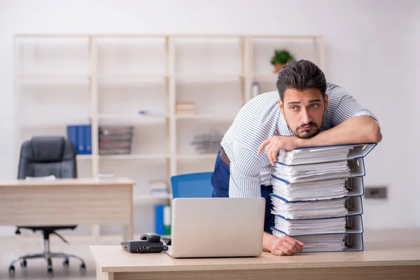 Young male employee and too much work in the office — Stock Photo, Image