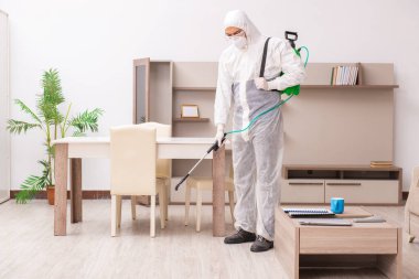 Genç erkek müteahhit evde haşere kontrolü yapıyor.