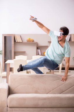 Evde sanal gözlük takan genç bir öğrenci.