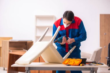 Genç erkek marangoz salgın sırasında ofiste çalışıyor.