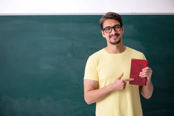 Joven estudiante masculino frente a pizarra — Foto de Stock