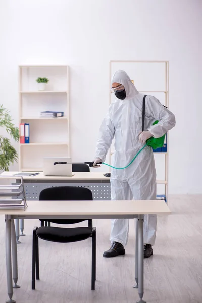 Contratista masculino joven desinfectando oficina durante pandemia — Foto de Stock