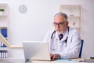 Hastanede çalışan yaşlı erkek doktor.