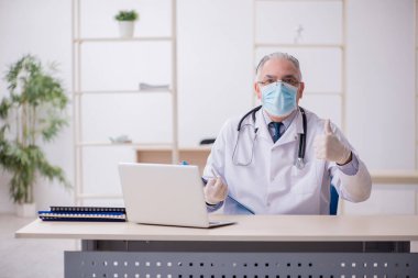 Klinikte çalışan yaşlı erkek doktor.