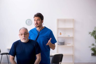 Yaşlı adam genç erkek doktoru ziyaret ediyor.