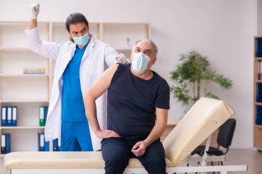Yaşlı adam covid-19 aşı konseptinde genç doktoru ziyaret ediyor.