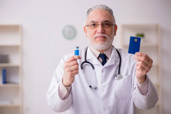 Yaşlı doktor kredi kartı tutuyor. — Stok fotoğraf