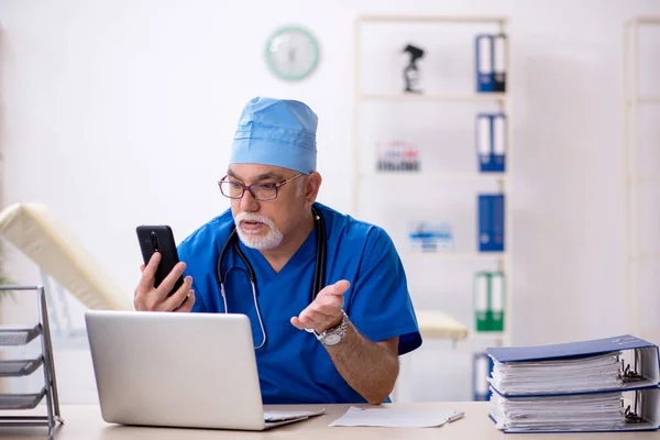 Oude mannelijke arts werkzaam in de kliniek — Stockfoto