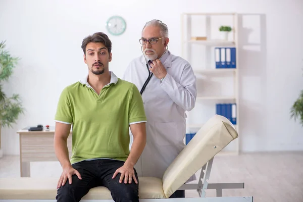 Giovane paziente maschio visita vecchio medico maschio — Foto Stock