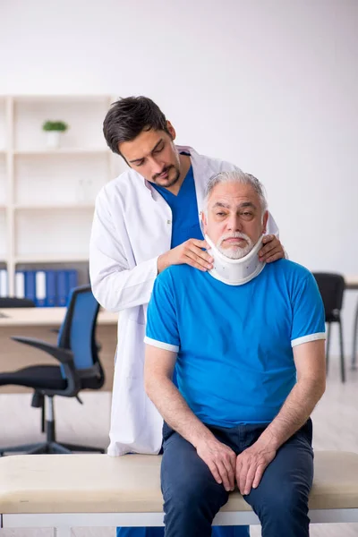 Yaşlı boyun yaralı erkek hasta genç erkek doktoru ziyaret ediyor. — Stok fotoğraf