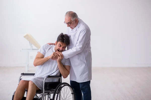 Old male doctor psychiatrist examining young disabled patient