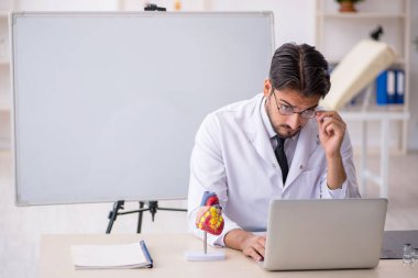 Sınıfta oturan genç erkek kardiyolog.