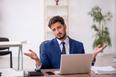 Ofisteki aşırı işten memnun olmayan genç bir erkek işçi.