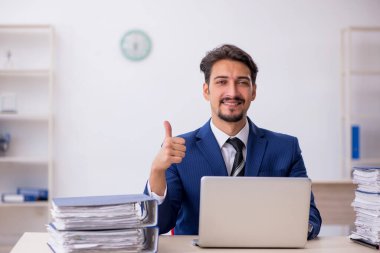 Genç bir erkek çalışan ve ofiste çok fazla iş var.