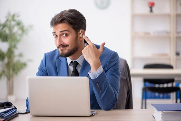 Deaf male employee using hearing aid at workplace — Stock Photo, Image