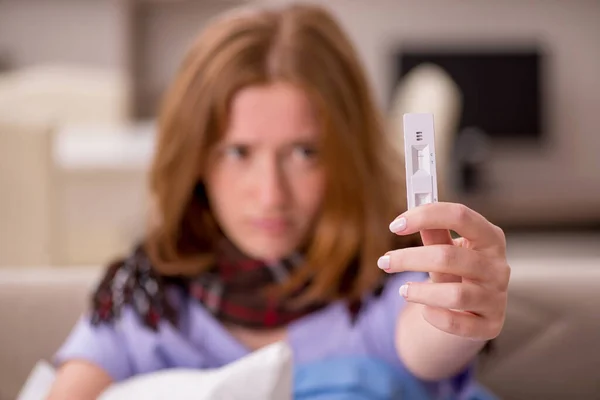 Jonge zieke vrouw die thuis zwangerschapstest houdt — Stockfoto