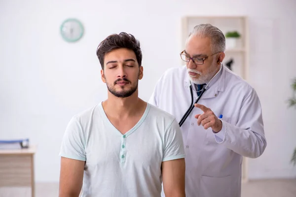 Jeune patient de sexe masculin visitant un vieux médecin — Photo