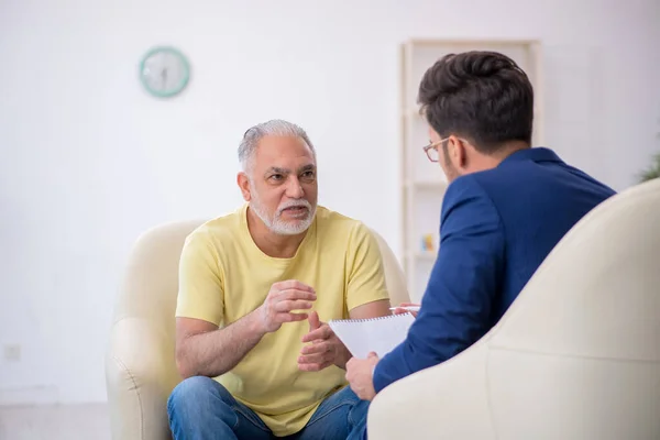 Viejo visitando joven psicoterapeuta masculino —  Fotos de Stock