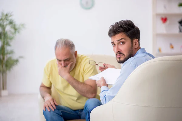 Vieil homme visitant un jeune psychothérapeute masculin — Photo