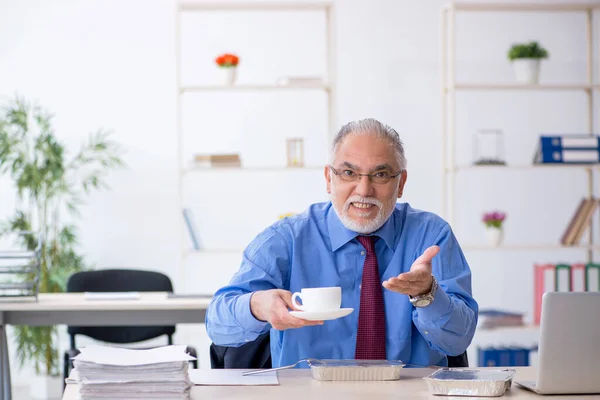 Eski erkek çalışan ofiste kahvaltı yapıyor. — Stok fotoğraf