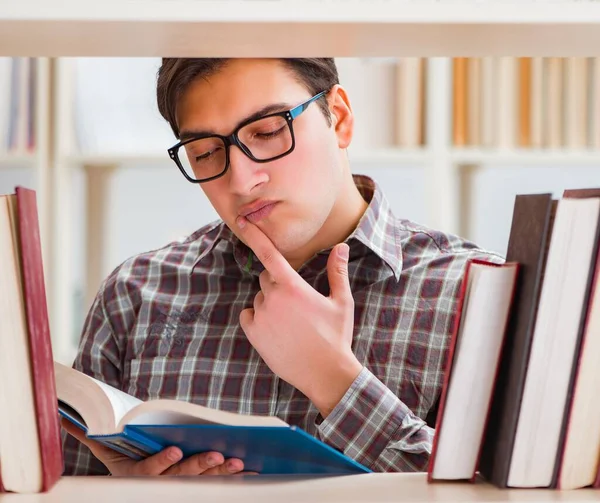 Młody student szuka książek w bibliotece uczelni — Zdjęcie stockowe