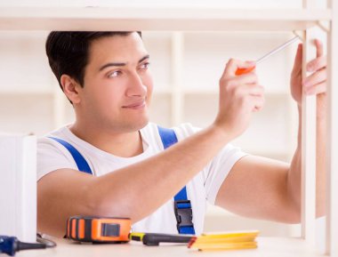 İşçi adam montaj kitaplığını tamir ediyor