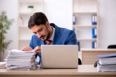 Genç bir erkek çalışan ve ofiste çok fazla iş var.