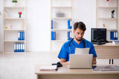 Klinikte çalışan genç erkek doktor.