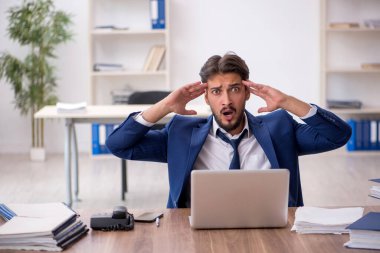 Ofisteki aşırı işten memnun olmayan genç bir erkek işçi.