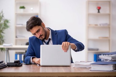 Ofisteki aşırı işten memnun olmayan genç bir erkek işçi.