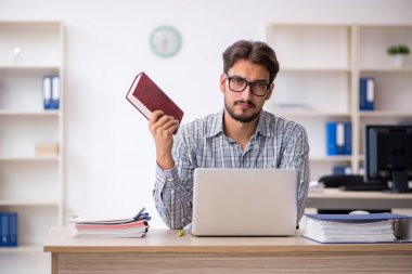 Genç erkek çalışan ofiste oturuyor.