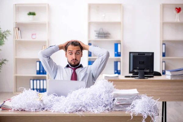 Ung manlig anställd och en hel del klippta papper på kontoret — Stockfoto