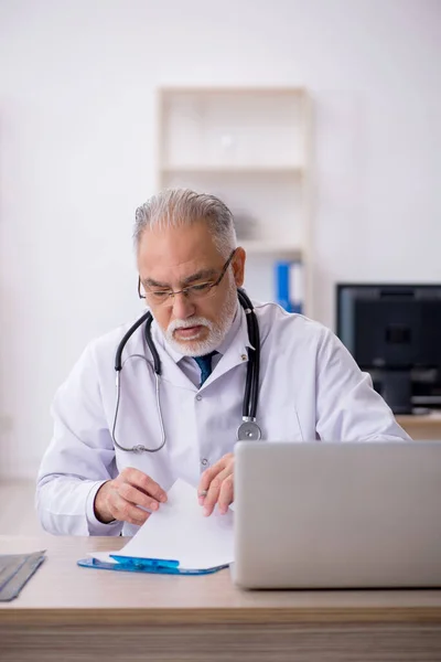 Klinikte çalışan yaşlı erkek doktor. — Stok fotoğraf