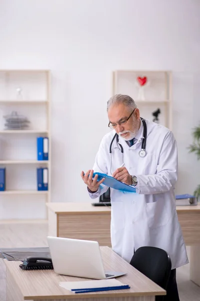 Klinikte çalışan yaşlı erkek doktor. — Stok fotoğraf