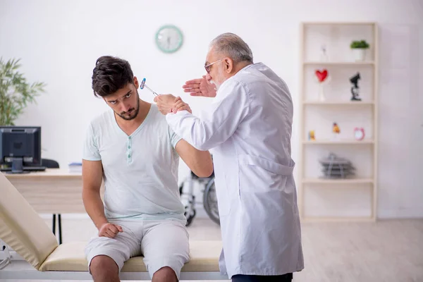 Jeune patient de sexe masculin visitant un vieux médecin neurologue — Photo